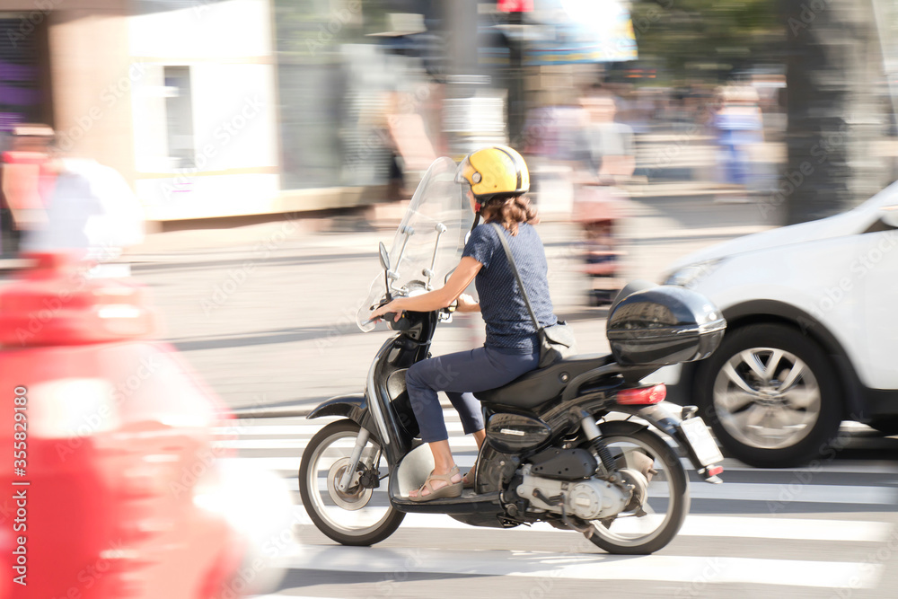 One woman riding a vespa scooter in the city street traffic