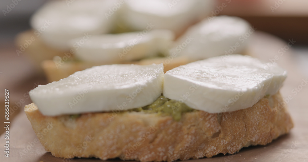 mozzarella slices on ciabatta slice with pesto on olive board