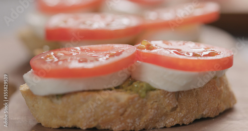 tomato on bruschetta with mozzarella and pesto on olive board