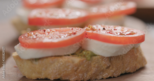 bruschetta with mozzarella, tomato and pesto on olive board