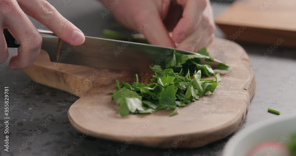 man chopping fresh parsley on olive board man chopping fresh parsley on olive board