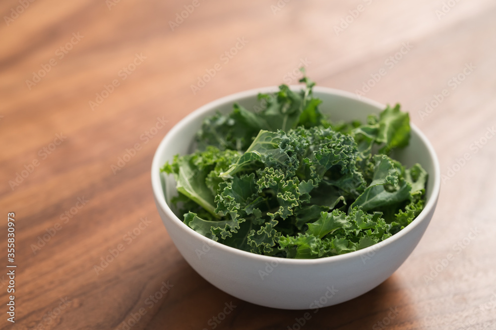 kale salad leaves in white bowl on walnut table with copy space kale salad leaves in white bowl on walnut table with copy space