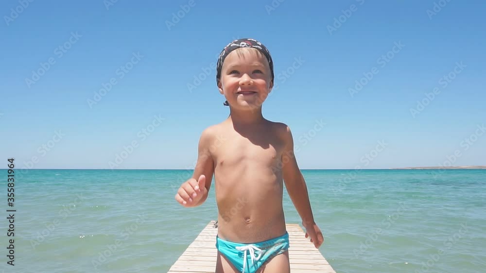 Baby, baby with blue eyes smiling posing for the camera, against the background of the azure sea and blue sky, Sunny clear day. Baby, baby with blue eyes smiling posing for the camera, against the background of the azure sea and blue sky, Sunny clear day.