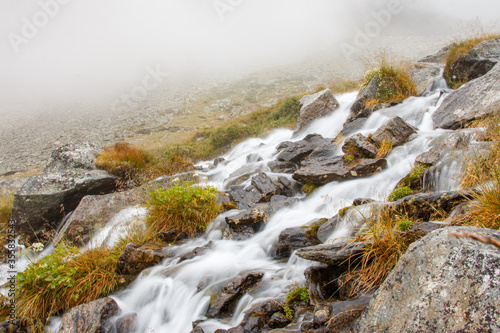 sanft rauschender weißer Gebirgsbach im Nebel photo