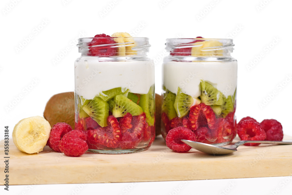 Two glasses of healthy layered snack with raw raspberry and kiwi fruits and yoghurt on white background Two glasses of healthy layered snack with raw raspberry and kiwi fruits and yoghurt on white background