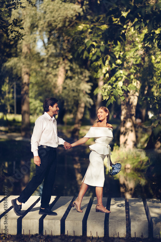 Happy Just-Married Couple Holding Hands Walking In Beautiful Park, Vertical