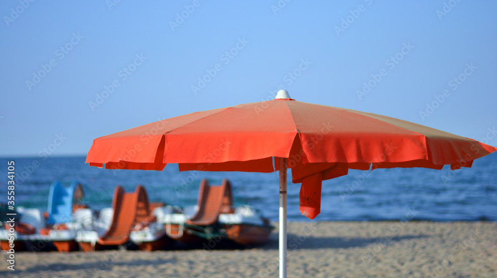 a red beach umbrella in front of the sea
