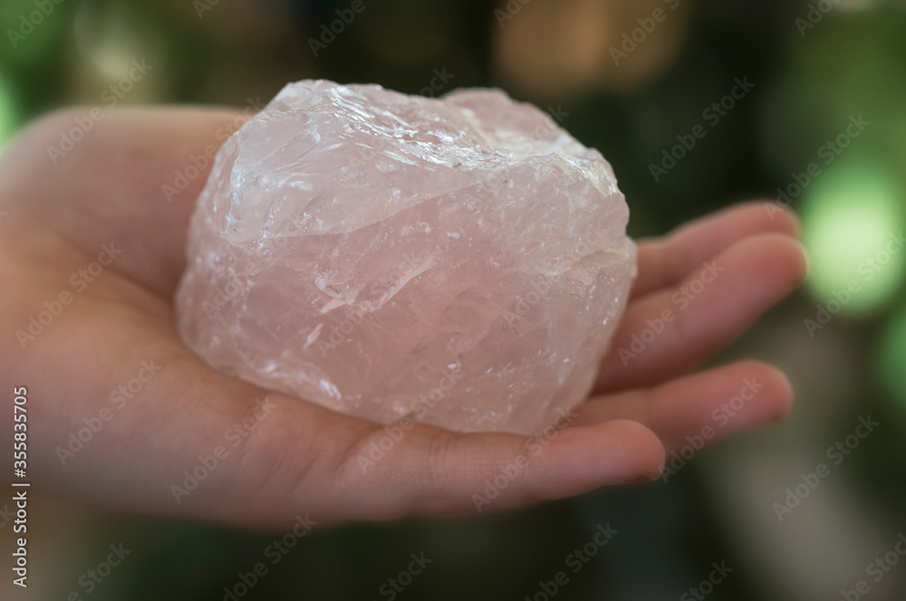 A raw pink rose quartz in the hand
