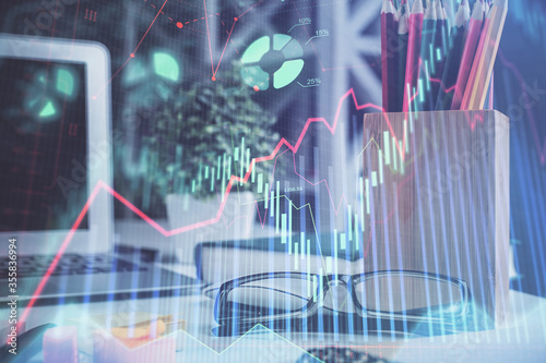 Financial chart hologram with glasses on the table background. Concept of business. Double exposure.