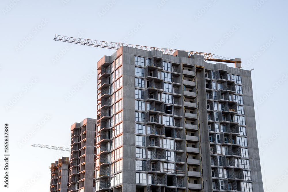 Tower crane against the blue sky during sunset. Construction of a new high-rise apartment building from concrete blocks and gas-silicate brick. Renovation program, concept of the buildings industry