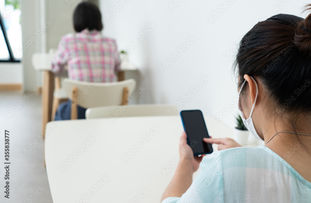 Asian woman wearing face mask and keep social distanicng by sitting on each table in the restaurant during covid-19 or coronavirus outbreak. new normal lifestyle concept Asian woman wearing face mask and keep social distanicng by sitting on each table in the restaurant during covid-19 or coronavirus outbreak. new normal lifestyle concept