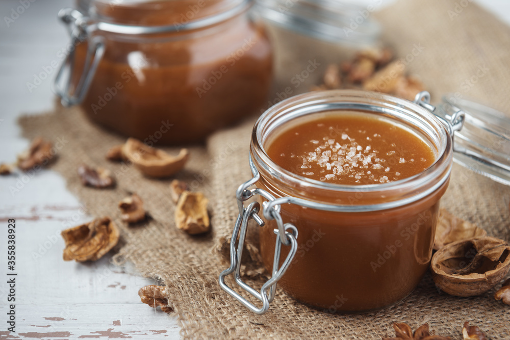 Two glass jars of homemade caramel with crystals of salt, nutshells and star anise Two glass jars of homemade caramel with crystals of salt, nutshells and star anise