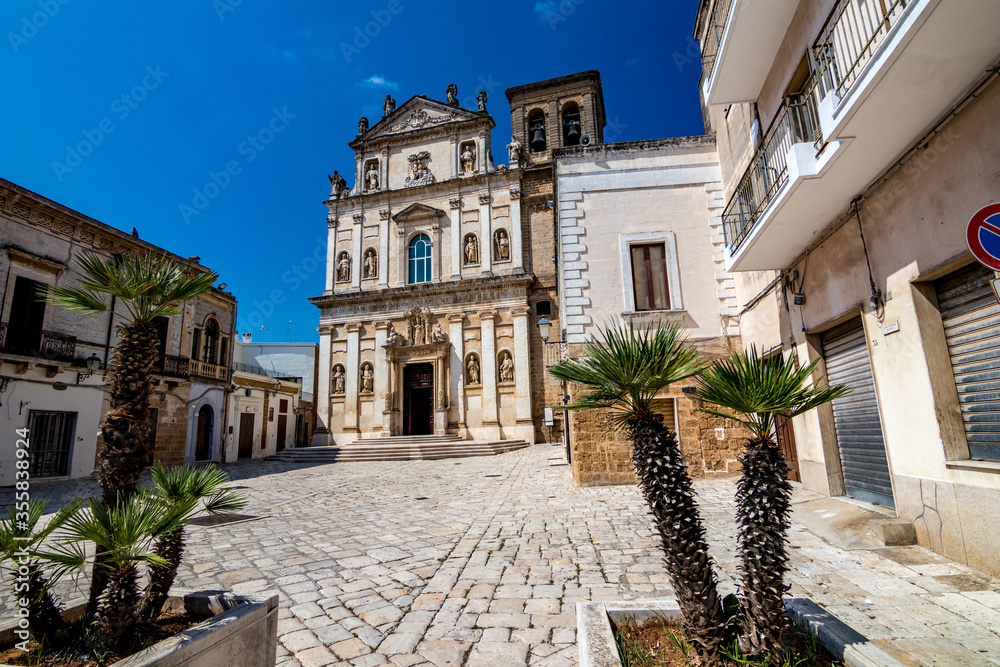 The old church of St. Anna, Mesagne. Puglia, Italy under the clear blue sky of a sunny summer day, travel photography, street view with few beautiful decorative palm trees in foreground