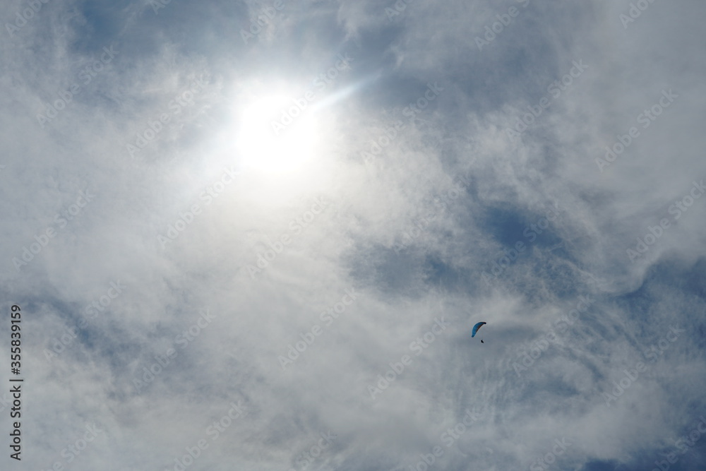 Massive cirrus sky scape covering the sun with a lonely paraglider chasing the wind under the sky.