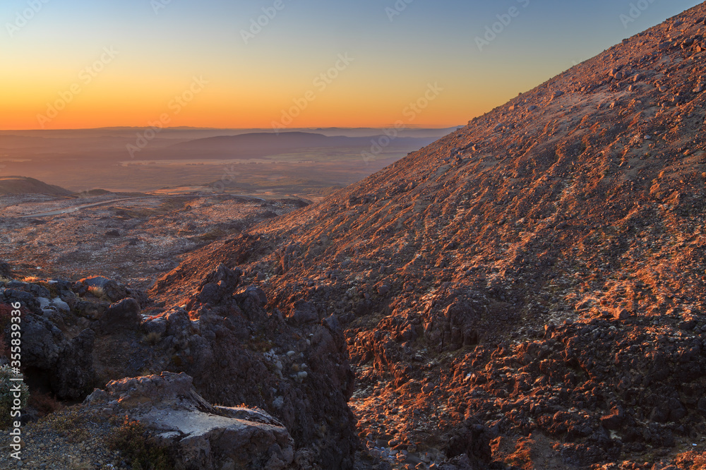 View from the rocky slopes of Mount Ruapehu, New Zealand, at sunset, looking down on the Volcanic Plateau