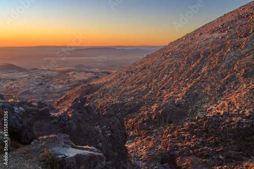 View from the rocky slopes of Mount Ruapehu, New Zealand, at sunset, looking down on the Volcanic Plateau