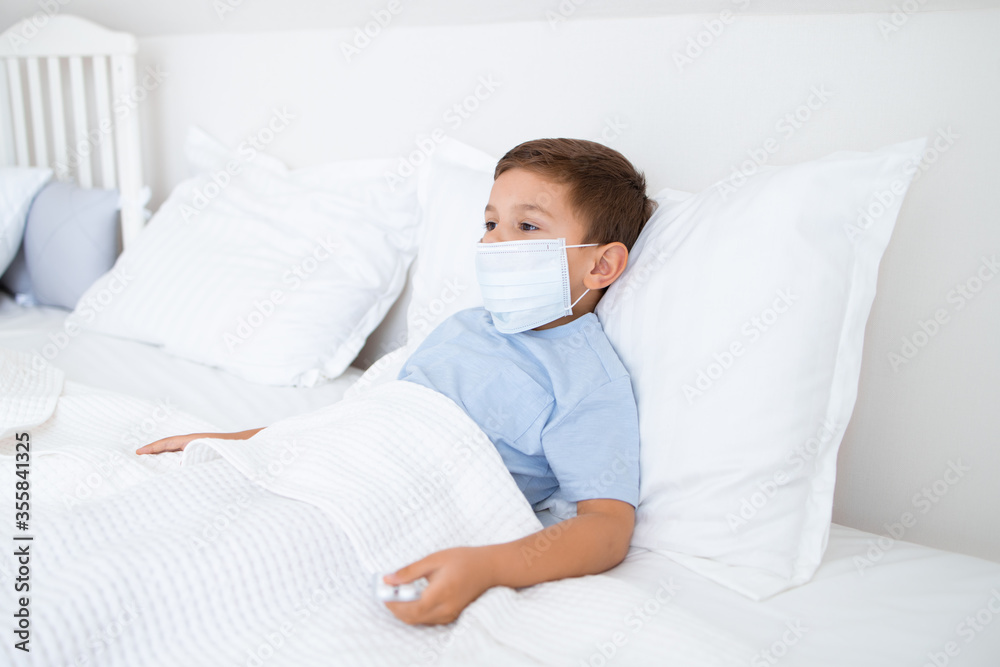 little boy lies in white bed sick with a medical mask little boy lies in white bed sick with a medical mask