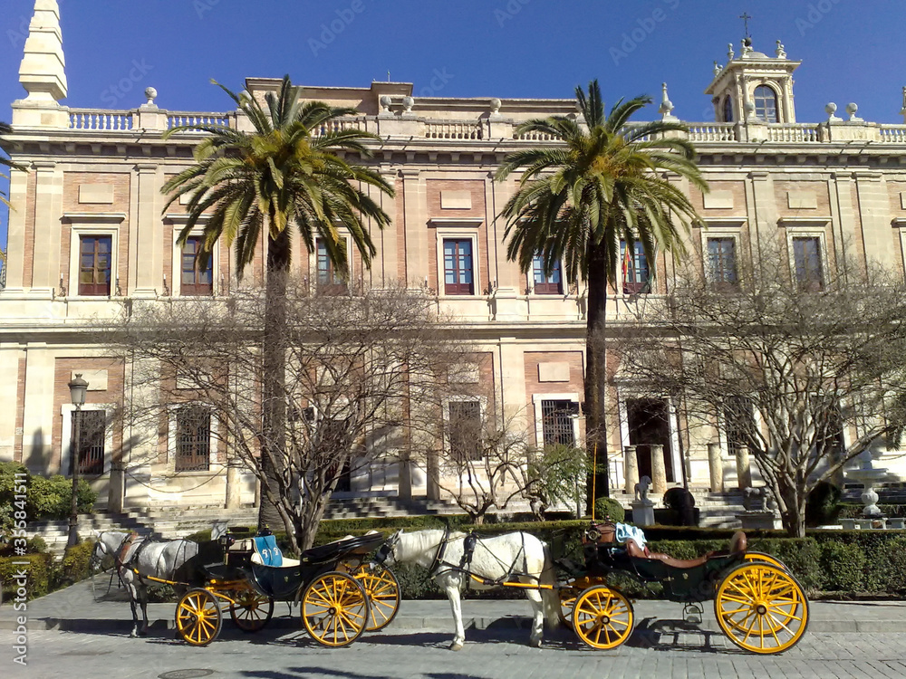 Fototapeta premium Horse-drawn carriages in front of the General Archive of the Indies building in Seville, Spain