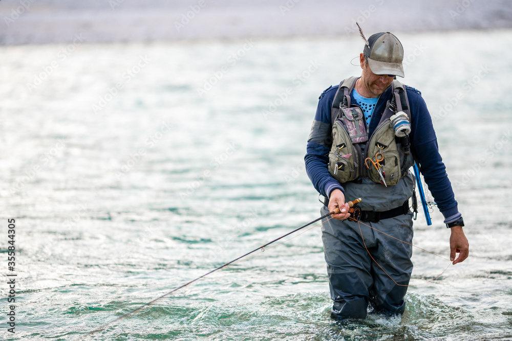 Close up of a fly fisherman wading in the river Close up of a fly fisherman wading in the river