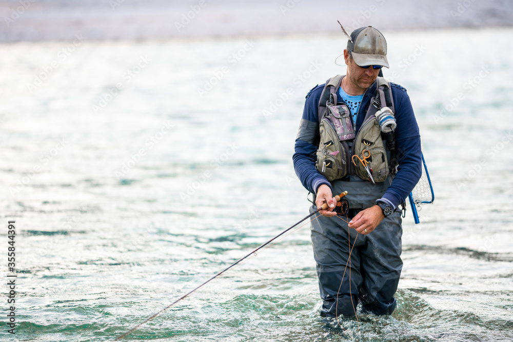 Close up of a fly fisherman wading in the river Close up of a fly fisherman wading in the river