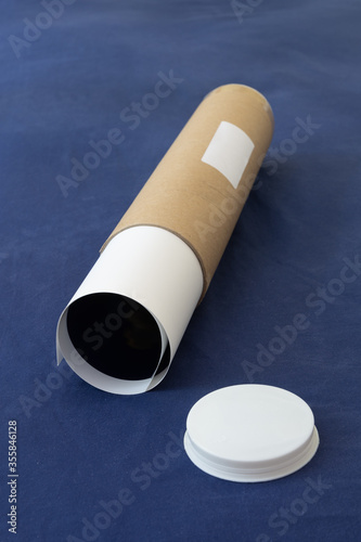 Fotografie, Obraz Labelled packaging tube for deliveries with end cap and rolled up paper contents