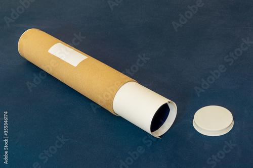 Fototapeta Labelled packaging tube for deliveries with end cap and rolled up paper contents