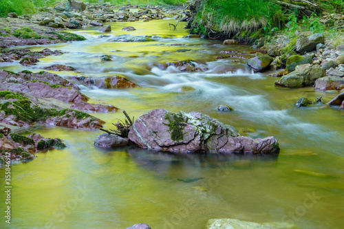 Long exposure picture of a stream flowing with rocks and natural light 