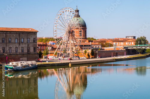 Toulouse landmarks on the bank of river Garone. Hospital de La Grave and Ferries Wheel reflected in Garone river.