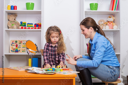 Toddler girl in child occupational therapy session doing sensory playful exercises with her therapist.