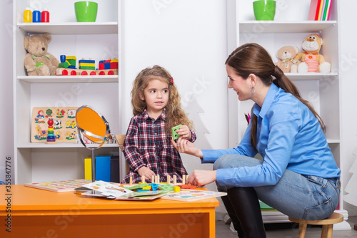 Toddler girl in child occupational therapy session doing sensory playful exercises with her therapist.