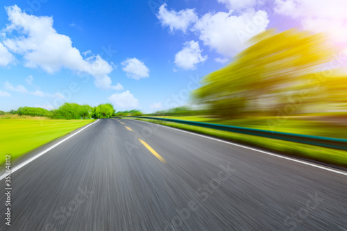 Motion blurred asphalt road and green tree landscape. © ABCDstock