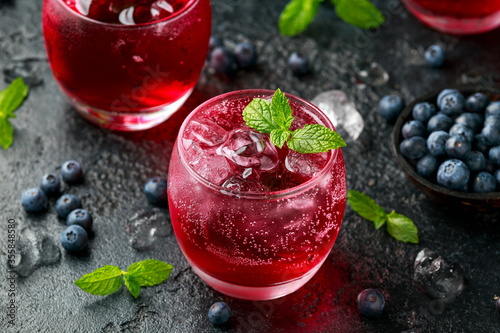 Refreshing Blueberry cocktail with ice and mint on rustic black table