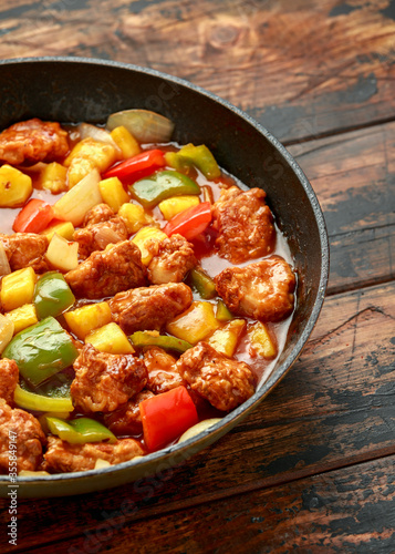 Pineapple and Chicken in sweet and sour sauce with bell pepper, rice and spring onion in pan