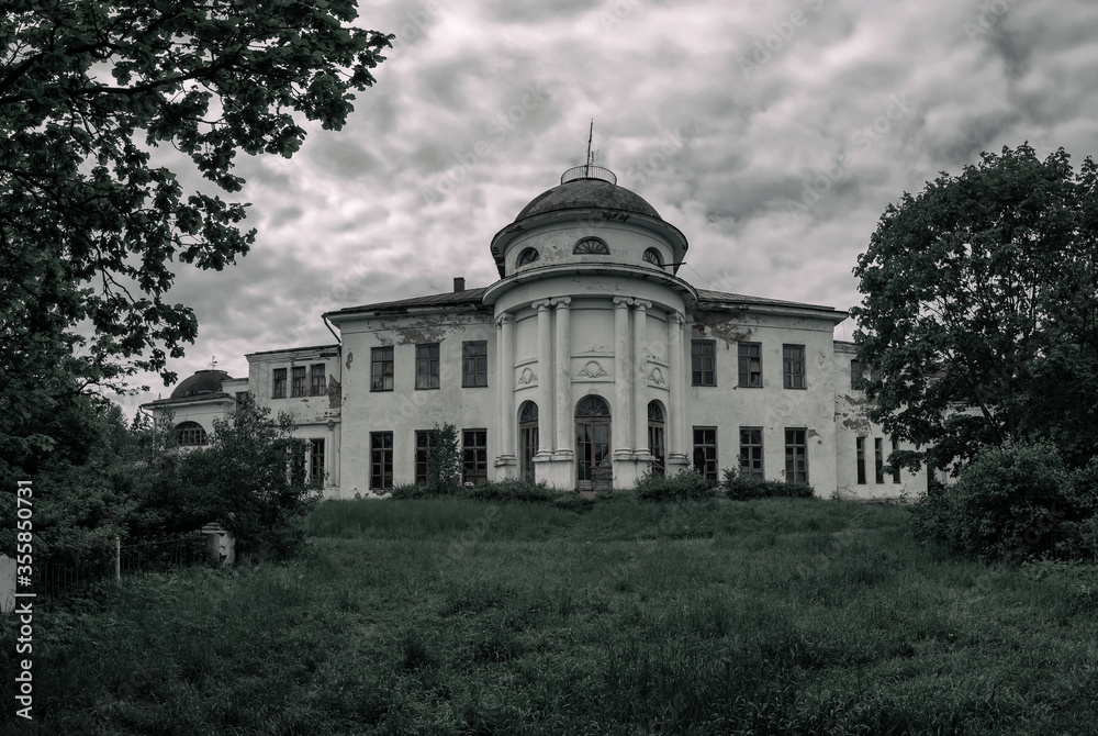 Beautiful abandoned manor stands in a clearing under a cloudy sky