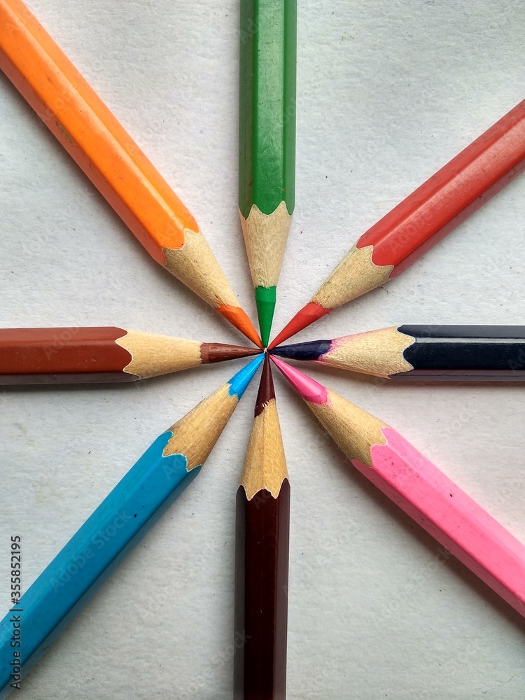 colored pencils on a wooden background connected through nip with eachother colored pencils on a wooden background connected through nip with eachother