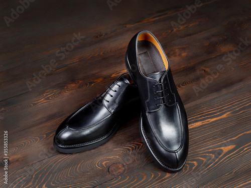 Black leather shoes of classic cut on a wooden background from dark abandoned boards