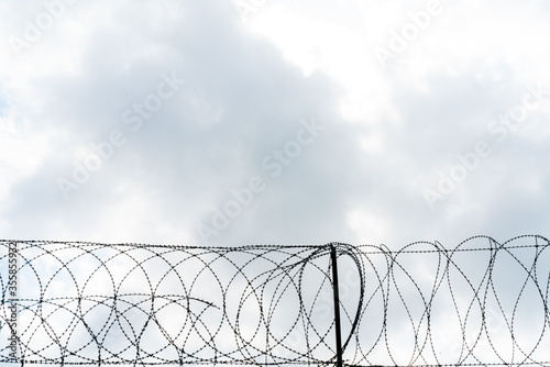 Barbed wire against sky. Metal fence. Restriction of freedom.
