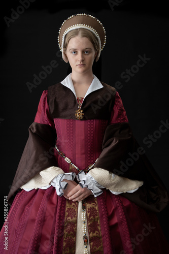 Foto A young woman in a red Tudor dress against a black bacdrop