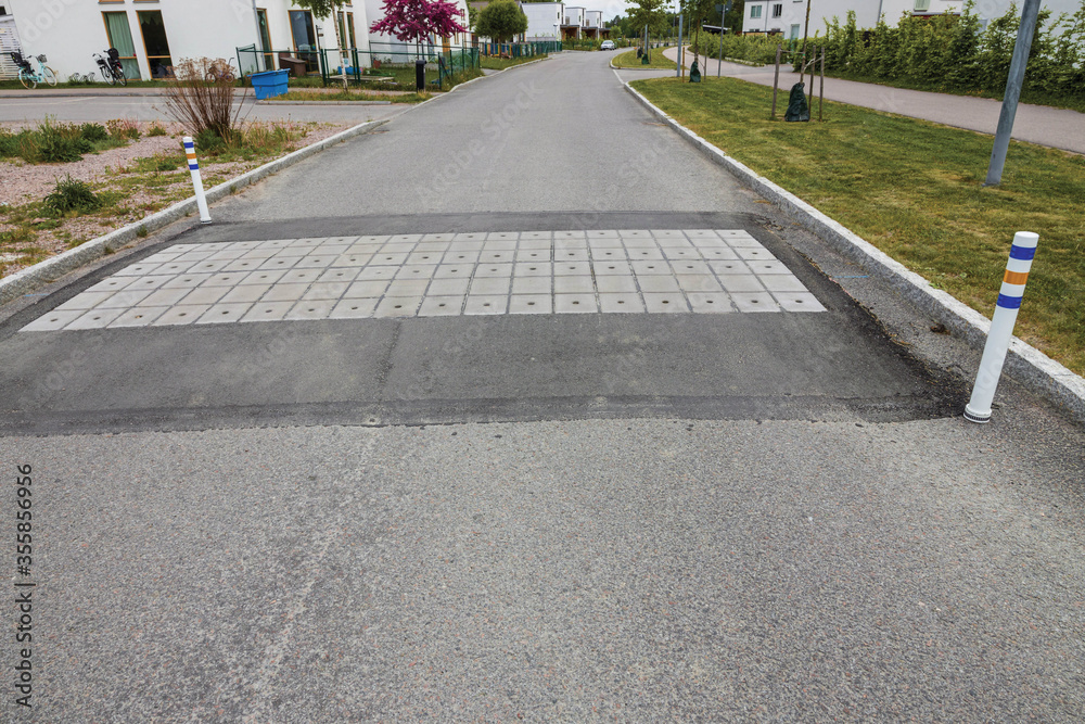 Close up view of speed bump on village street road. Landscape view background. Europe. Sweden.

