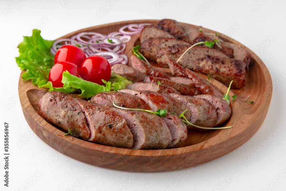 Homemade sausage in a natural shell with onions and sauce. Banquet festive dishes. Gourmet restaurant menu. White background.