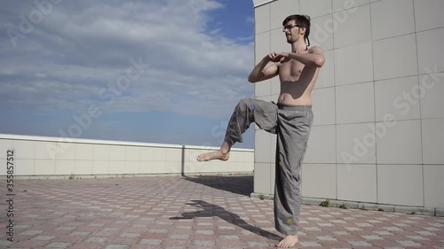 A man plays sports on the roof. A complex set of exercises based on gymnastics and karate.