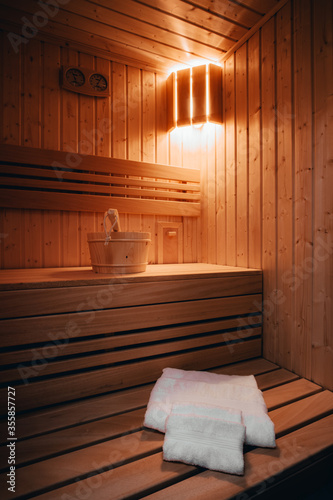 Private wooden sauna with folded towels, wooden bucket and a wooden spoon. 