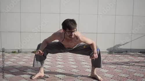 A man plays sports on the roof. A complex set of exercises based on gymnastics and karate.