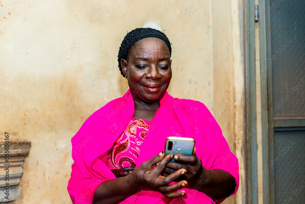 Fototapeta premium cheerful excited old black african woman receiving some good news with her smart phone.happy senior lady using mobile phone