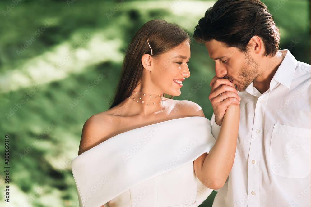 Loving Groom Kissing Bride's Hand Standing In Beautiful Park Loving Groom Kissing Bride's Hand Standing In Beautiful Park
