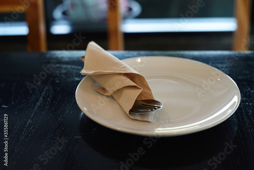 White dish and spoon on wooden table in restaurant