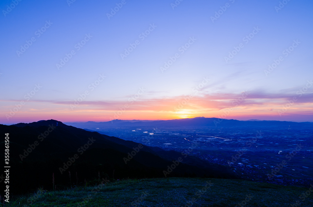 Fototapeta premium 山に沈む夕焼けと河と平野
