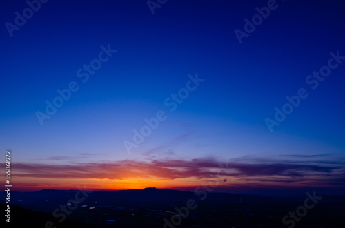 山に沈む夕焼けと河と平野