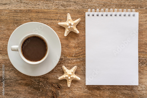 Coffee cup, blank notebook paper on wooden background. Morning, breakfast, coffee break concept. Top view.