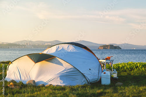 camping in the middle of a field by the sea with a view of the city at sunset. Camping and outdoor concept.